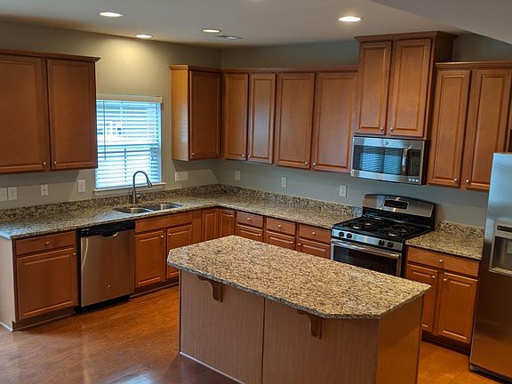 Large kitchen with granite counter tops, center island, gas stove, stainless steel appliances and plenty of cabinets.
