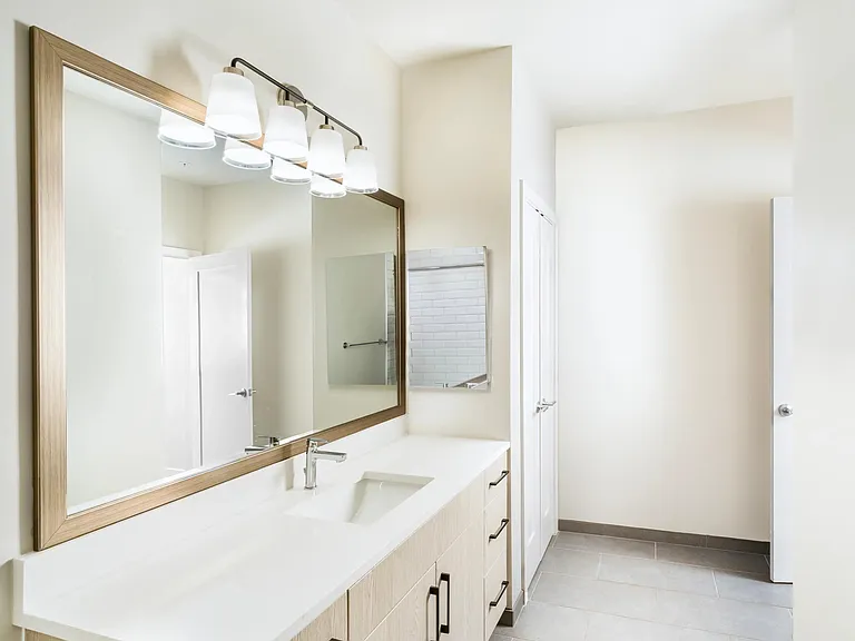 Primary bathroom with a long quartz vanity, integrated lighting, and clean-lined cabinetry arranged for an organized, comfortable daily routine.