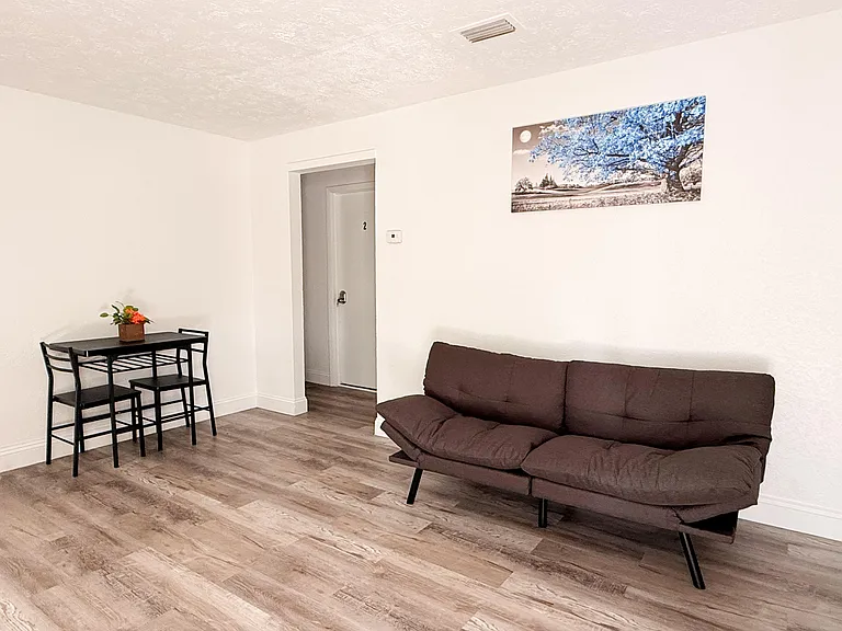 Open living area with durable plank flooring, comfortable seating, and a compact dining nook for everyday meals.