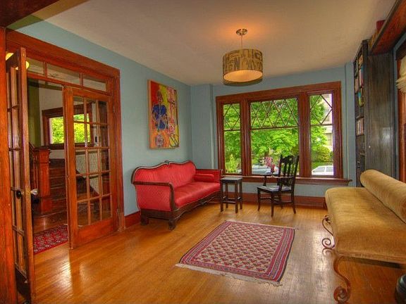 The formal living room features the French doors, hardwood floors, leaded glass windows & high ceili
