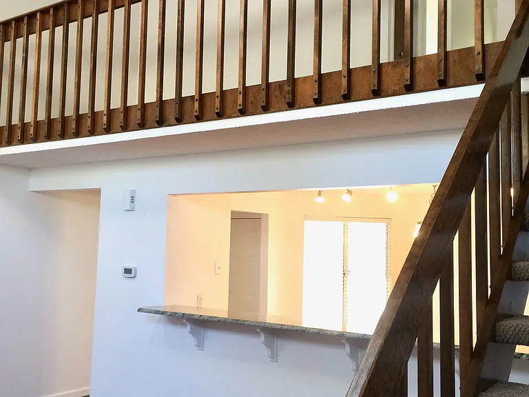 View of kitchen pass through and breakfast bar, with loft area above