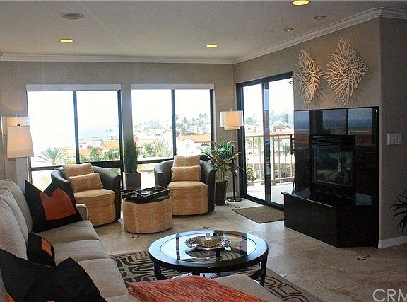 Another view of the living room, which features a gas fireplace, travertine flooring & crown molding