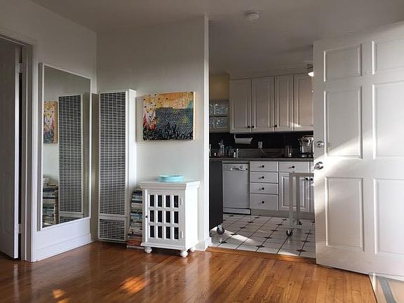 Entrance door into living room with kitchen to the right and bedroom straight back
