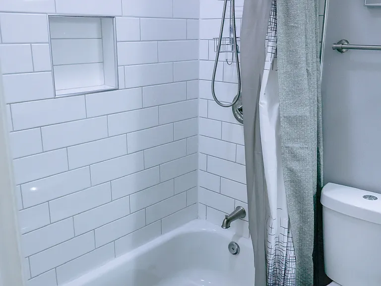 Updated bathroom featuring classic subway tile surround, built-in niche, and tub/shower combination for both style and functionality.