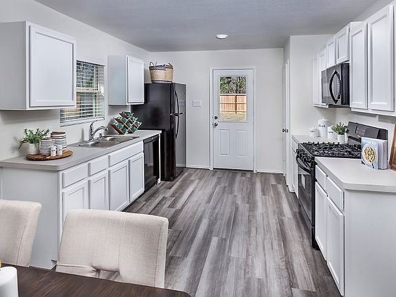 This lovely kitchen highlights designer cabinets with ample storage space, stylish black appliances
