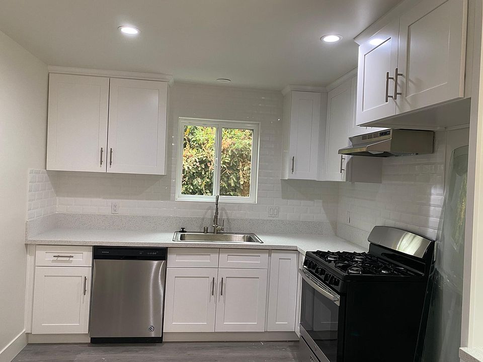 Tile surround for backsplash with large farm sink and quartz countertop.