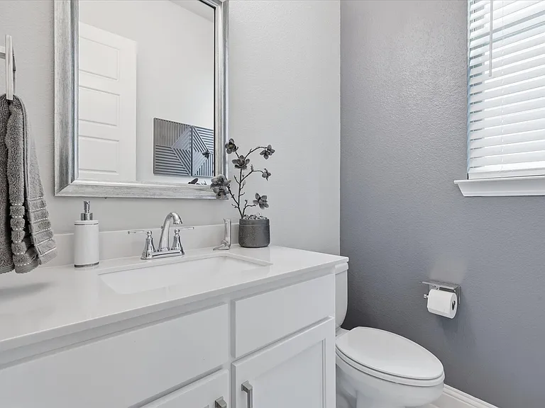 Powder bathroom with a white vanity, rectangular sink, chrome faucet, and a large framed mirror.
