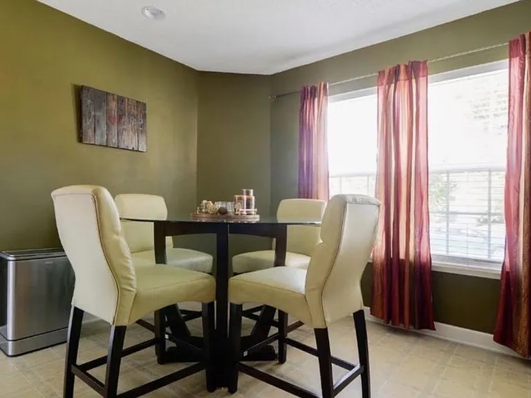 Dedicated dining area with a counter-height table, seating for four, and a large window with curtains for natural light.