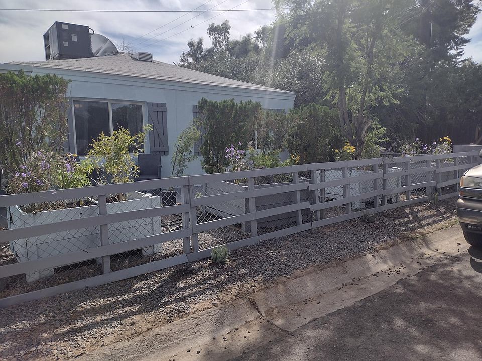 Front of house with large planter boxes full of flowers and sitting area out front