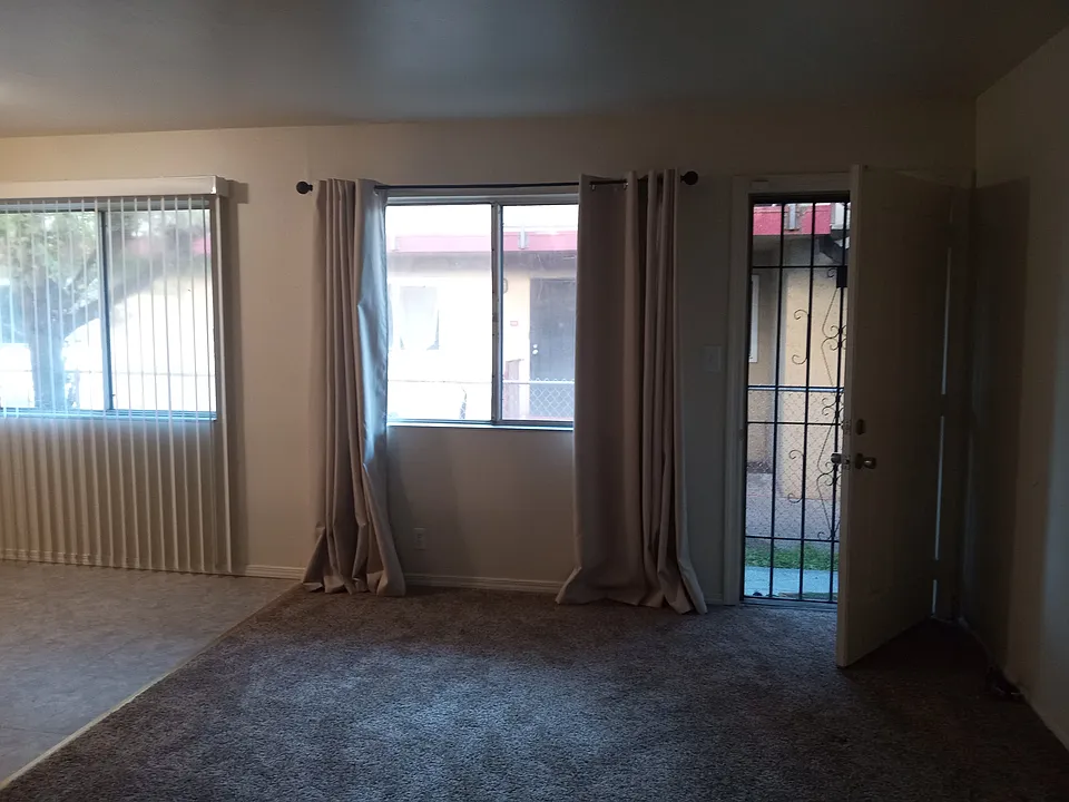 Front door into living room with a partial view of the dining area - new carpet, new blinds, new dining room light fixture, new door locks
