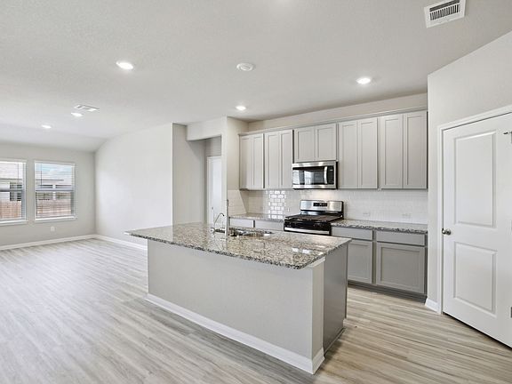 The kitchen features stone-colored cabinets and granite countertops.