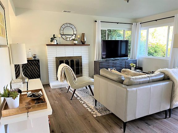 Cozy fireplace in living room that looks out towards front yard and hedges
