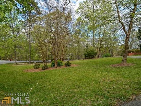 Stunning front yard features lush lawn & mature hardwoods