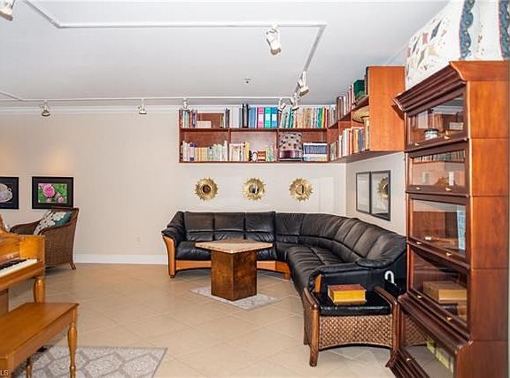 Living room area with built in book shelves, tile flooring and track lighting.