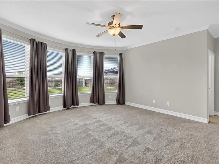 Expansive room featuring a bay window with five individual window units, neutral carpeting, and a ceiling fan with integrated lighting
