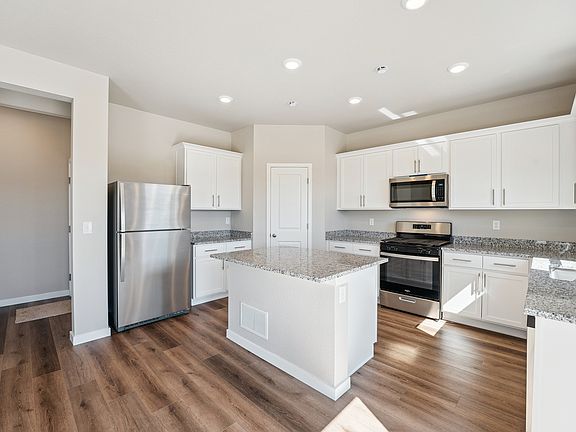 Designer kitchen with a large islands, sparkling countertops, and white cabinetry.