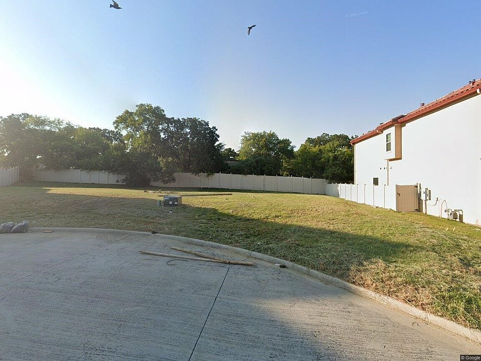 Expansive lot featuring a concrete paved area, grassy terrain, and a perimeter fence