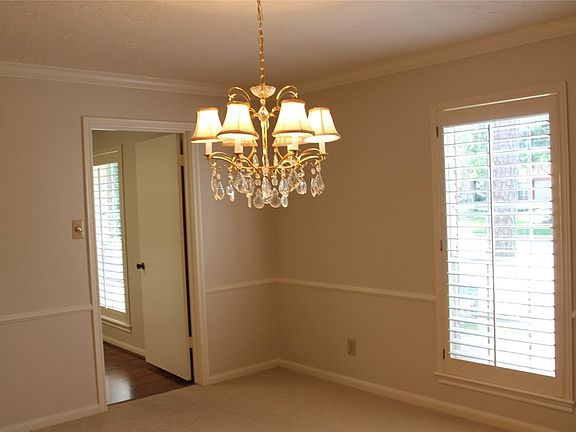 The formal dining room with chair rail wainscoting and pretty chandelier. Wood shutters on the large window.