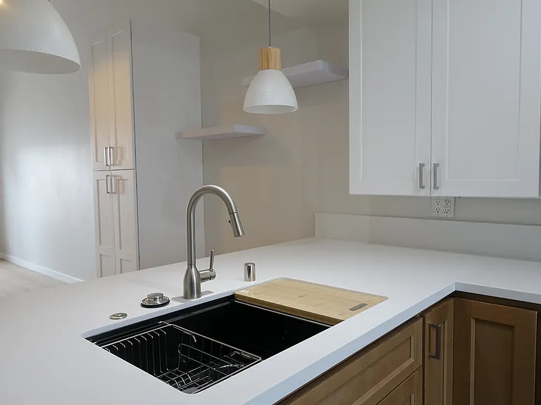 Kitchen: Bar seating with white/oak pendant lights. Undermount sink with fitted prep accessories and overhead recessed light.