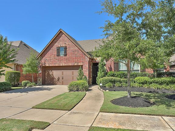View of sidewalks, trees, lush landscaping and wrought iron entry gate that is not only beautiful but functional as well.
