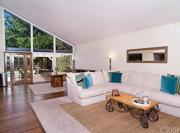 The open and bright floor plan with welcoming living room and dining area, flooded with natural light from the bank of windows overlooking the pool area.