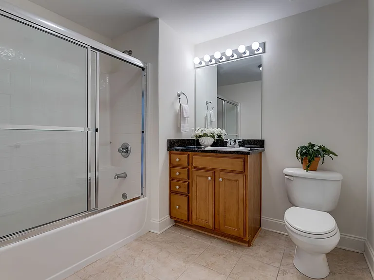 The second bath has lots of space & glass doors on the tub/shower. There is room for another cabinet or piece of furniture in this bath.