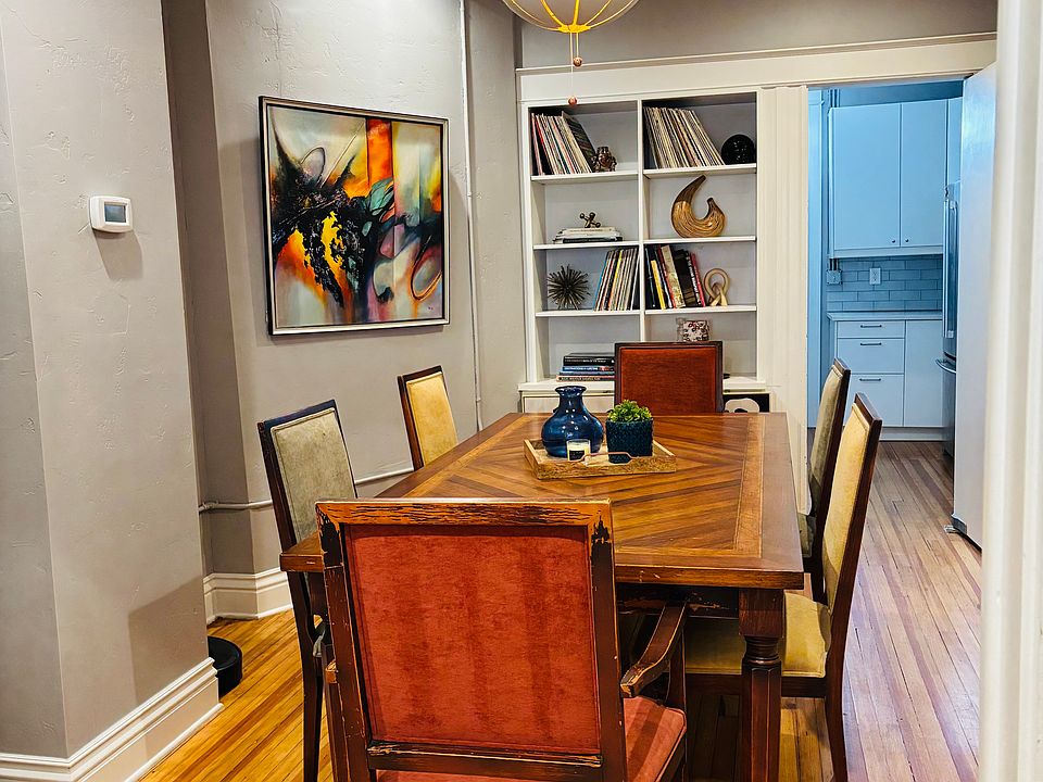 The dining room is a masterpiece of character and elegance. A beautiful wood table complements the intricate crown molding and a built-in bookshelf, adding warmth and charm to the space. Gorgeous art adorns the walls, and can be enjoyed from all angles