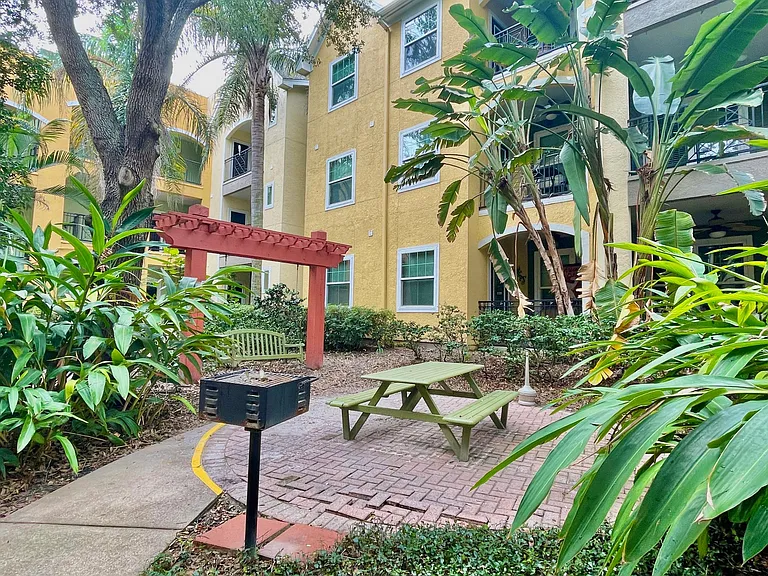 Courtyard outside of condo with grill, picnic table, and bench swing