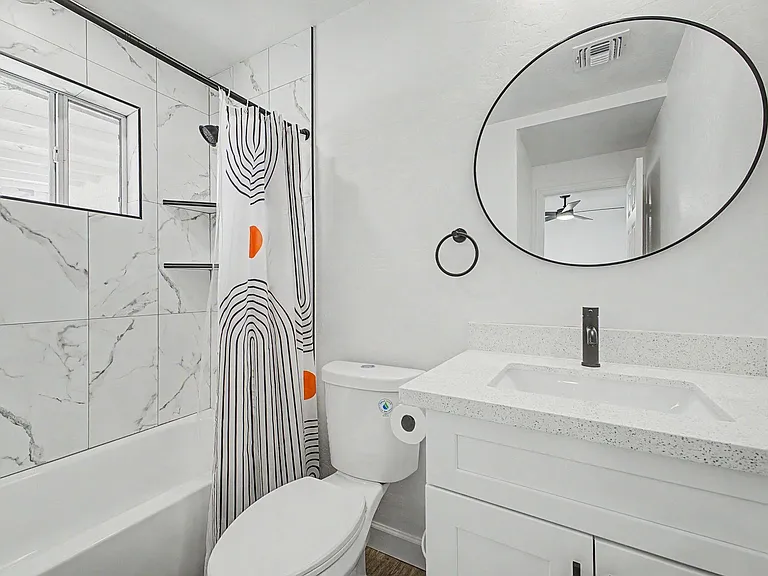 Updated bath with tiled tub/shower surround, wide vanity with solid-surface top, and a large mirror for daily routines.