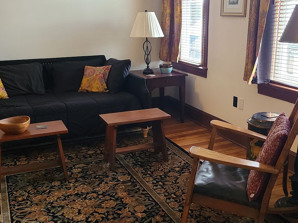 Comfortable living room with ample seating. Adjustable wood blinds and curtains on windows - open to let the sun stream in!