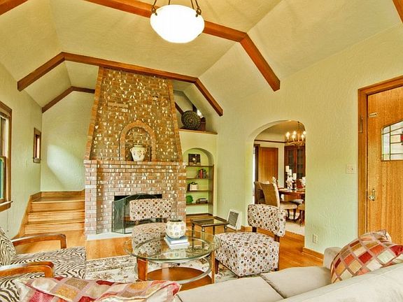 Classic high ceilings, box beam, staircase going up to master behind custom wood-burning fireplace.