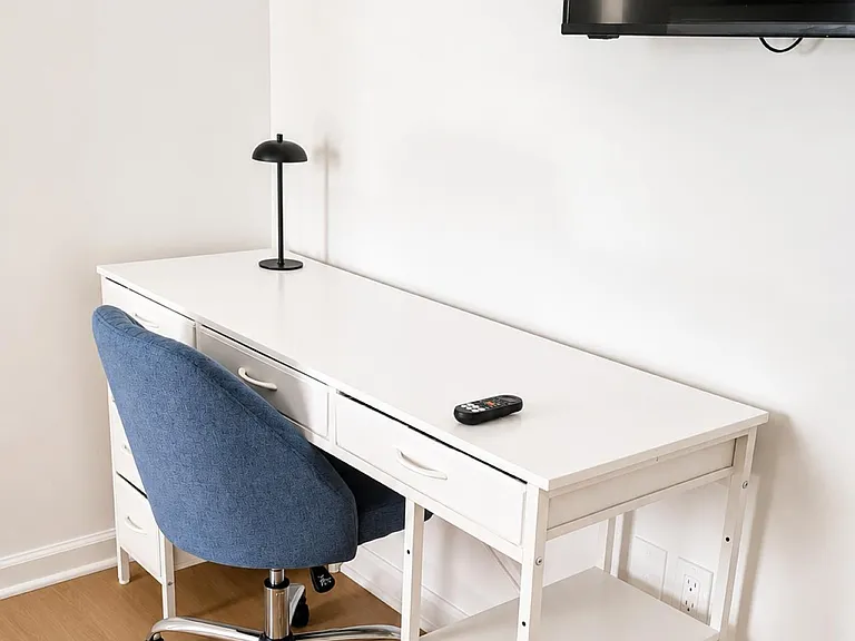 Dedicated work area with a full-size desk, task lamp, and rolling chair, plus wall-mounted 50' TV for added convenience.
