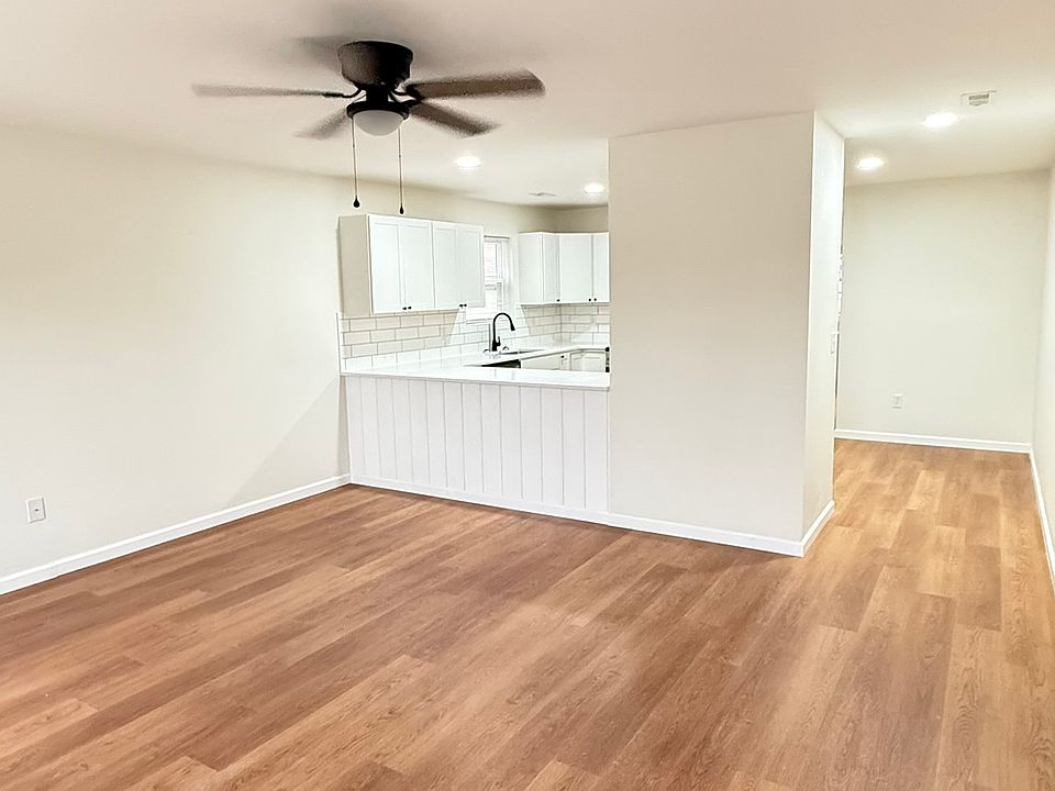 Living Room: Bright, spacious living room with a large window offering plenty of natural light, a ceiling fan, and an open-concept layout that flows seamlessly into the kitchen, creating a comfortable and inviting living space.