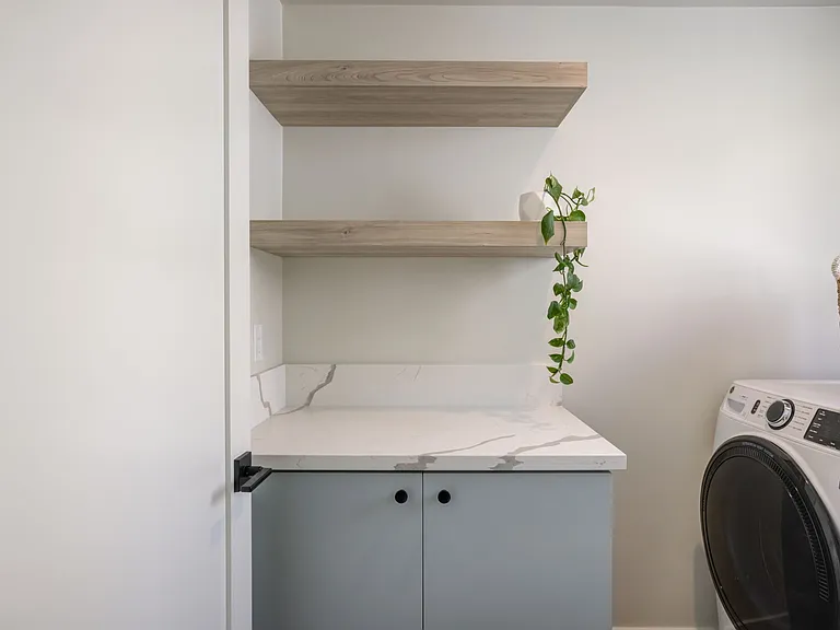 Dedicated laundry room with a door for privacy, natural light from a window, and additional storage space.