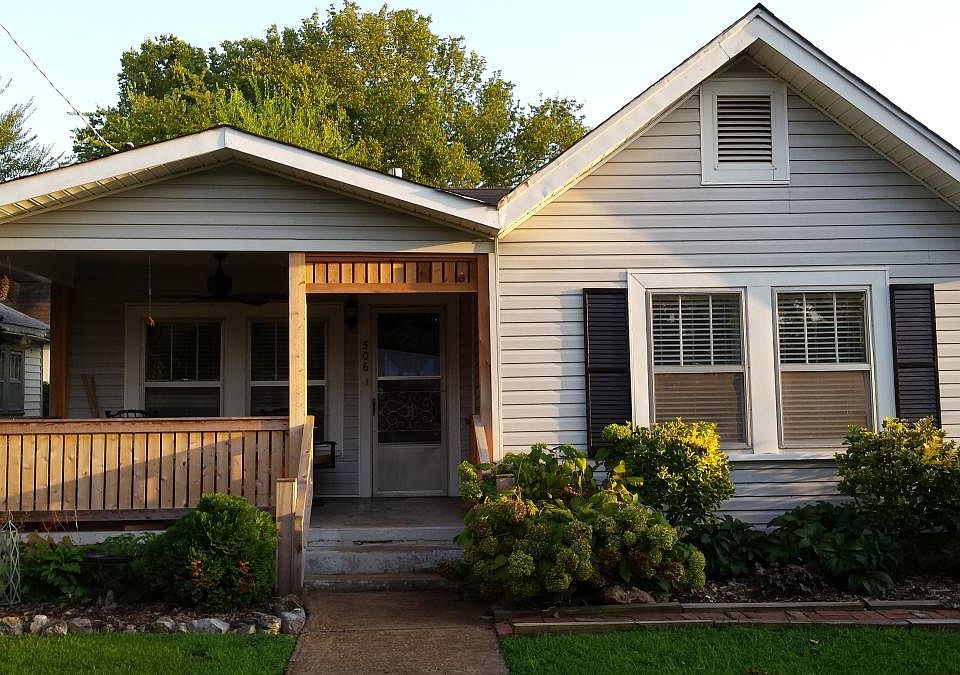 Gated front porch has a ceiling fan overhead.