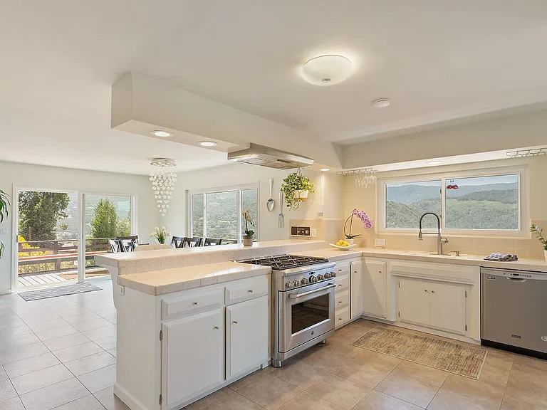 Chef's kitchen with stainless steel gas range, dishwasher, and disposal.