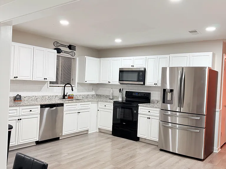 Spacious kitchen with ample white cabinetry, granite-look counters, and stainless steel appliances including a French-door fr