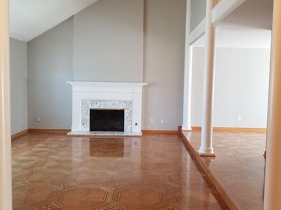 Living room from foyer view, featuring vaulted ceilings, and fireplace, Kitchen and dining room are off on the right side