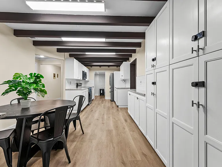 Galley-style kitchen with ample white cabinetry, stone-look counters, stainless appliances, and adjacent dining nook.