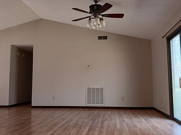 Combined living and dining area with vaulted ceiling and sliding door to back yard. View from kitchen