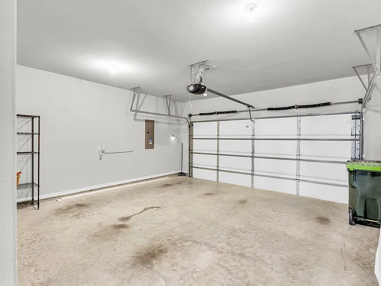 Spacious garage with a sectional overhead door, automatic opener, and concrete flooring