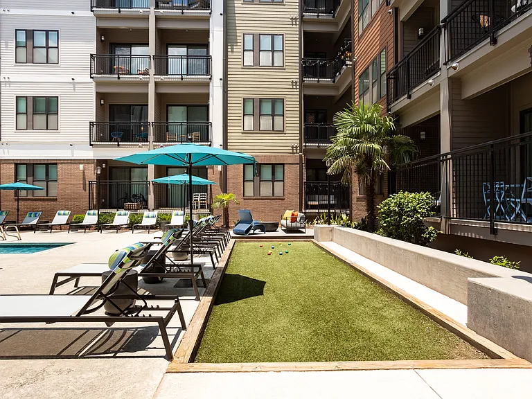 Shaded Pool Deck with Lounge Chairs and Adjacent Bocce Ball Court