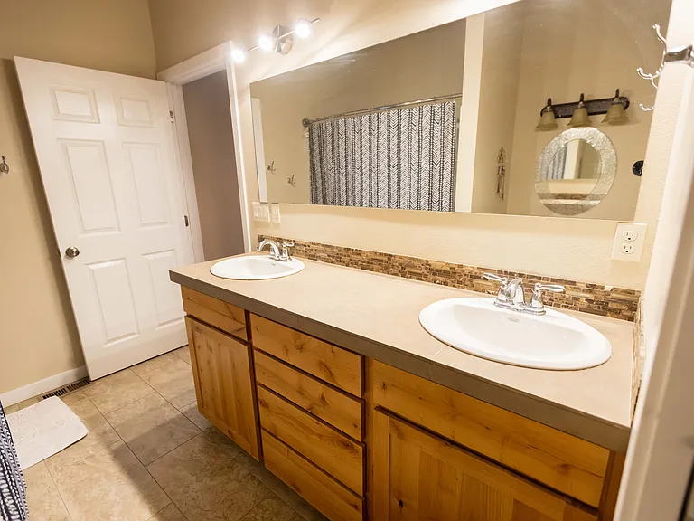 Master bathroom has shower/tub combo, two sinks, a make up station, and a pocket door that leads into an additional room with lavatory.