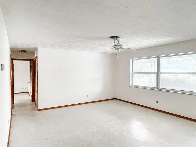Looking back the hallway towards the 2 bedrooms and full bath. Kitchen is on the other side of the wall to the left. (Blinds will be added to front window. Also, please note that terrazzo floors will be repaired later this week around edges where carpetin