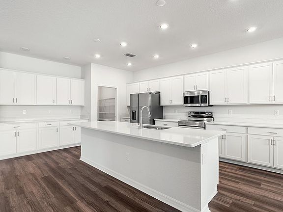 The spacious kitchen wows with a large island, bright lighting, and ample cabinet and counter space