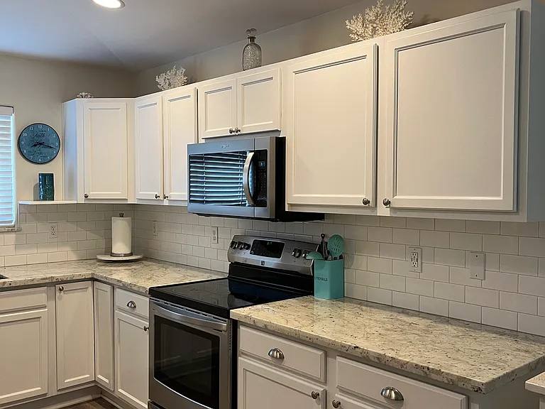 Kitchen: stainless steel appliances granite counters, white backsplash and gray laminate flooring