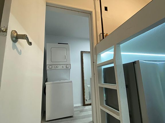 Washer and dryer in bathroom, full length mirror and ladder seen.