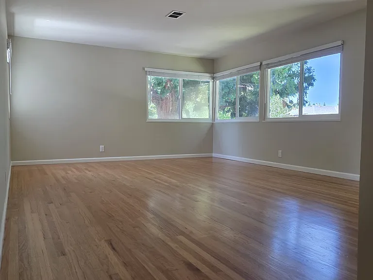 Large living room with hardwood floors and dual pane windows. View from entering the front door.