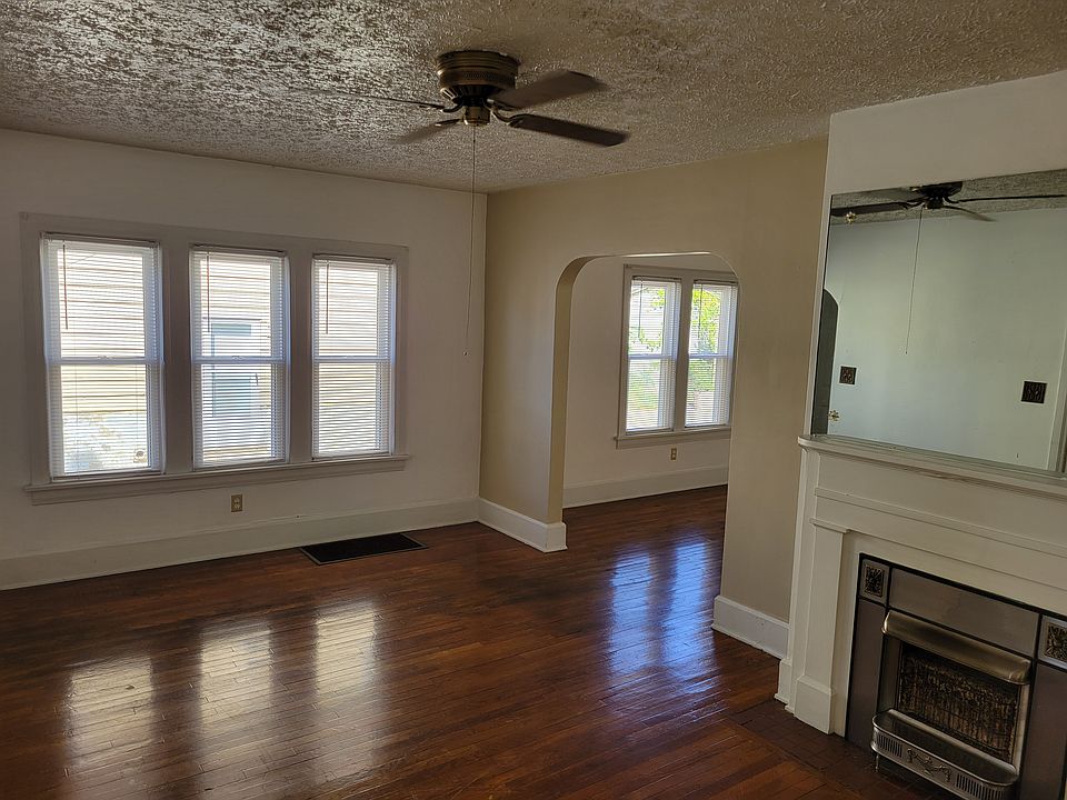 Livingroom leading to dining room with gas fireplace, mirror, ceiling fan and new windows.