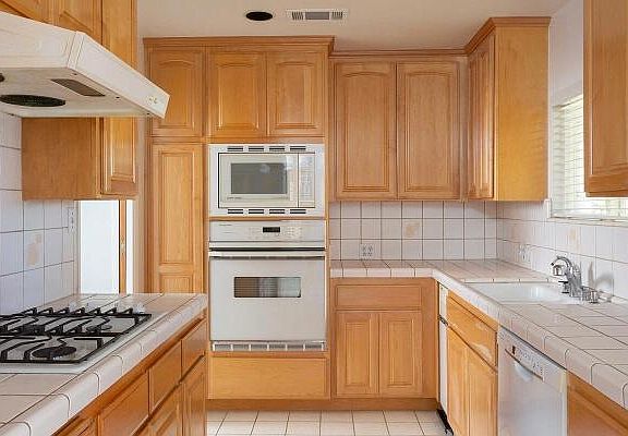 Kitchen with new dishwasher and range and water filtration system. Sliding door separating the kitchen from the living room area.